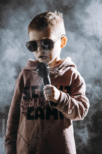 Chłopiec śpiewa do mikrofonu, refleksyjnie, nostalgicznie, przejmująco, smutne piosenki, dziecięca twórczość muzyczna