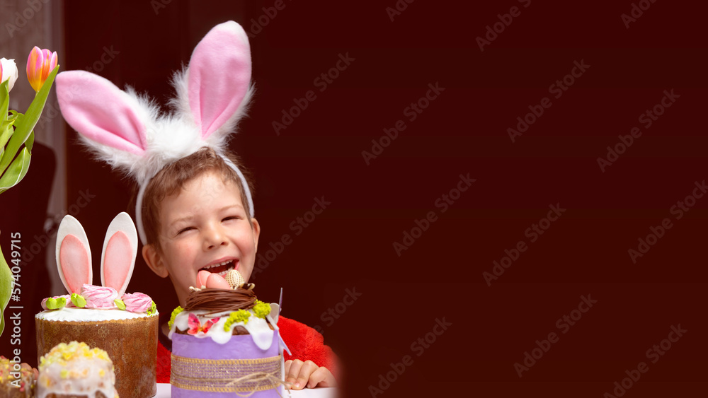 Cute little boy with bunny ears looking at tasty easter sweet cake