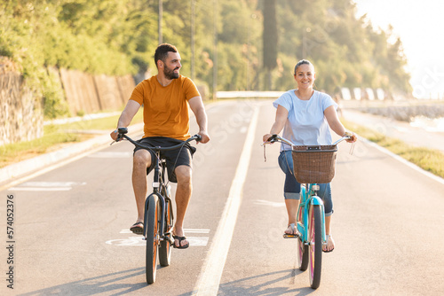Photography Caucasian couple taking pleasure in the ride on beach cruiser bikes, pedaling on