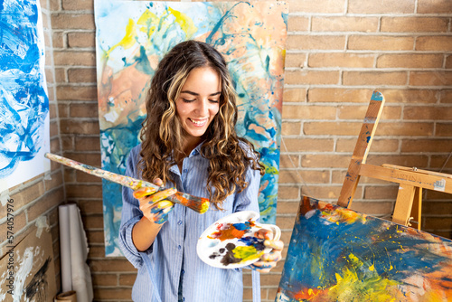 Young caucasian woman with brush painting at studio art - School, art, creativity and people concept