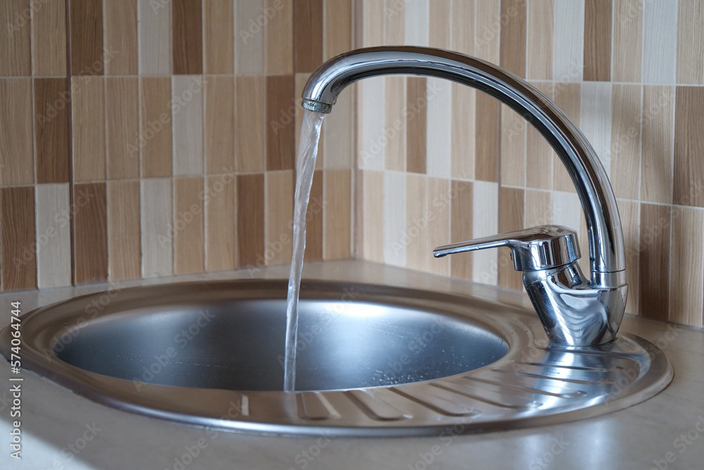 Water pours in a strong stream from the tap in kitchen Water pours in a strong stream from the tap in kitchen