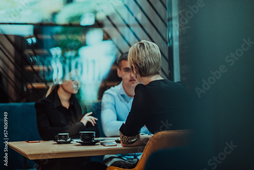 Photo through the glass of a group of business people sitting in a cafe and discussing business plans and ideas for new online commercial services