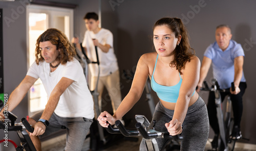 Men and woman taking indoor cycling class at fitness center  doing cardio riding bike