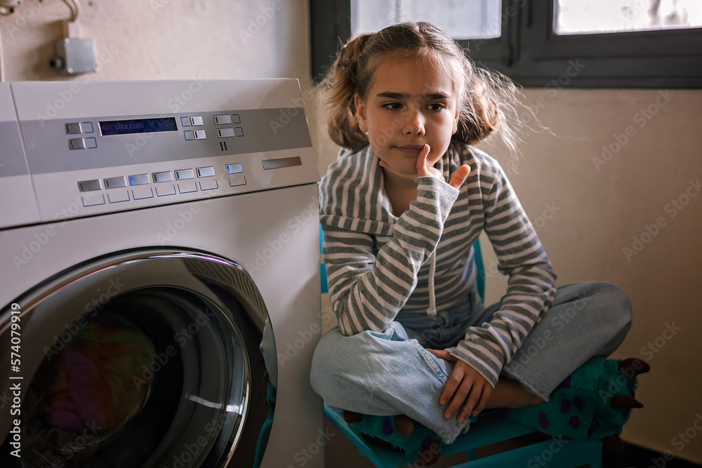 Eco-conscious teenage girl waits in common laundry. Sustainability and responsible living. Efforts to save resources, conserve water, energy, and money. Eco-lifestyle in action Eco-conscious teenage girl waits in common laundry. Sustainability and responsible living. Efforts to save resources, conserve water, energy, and money. Eco-lifestyle in action