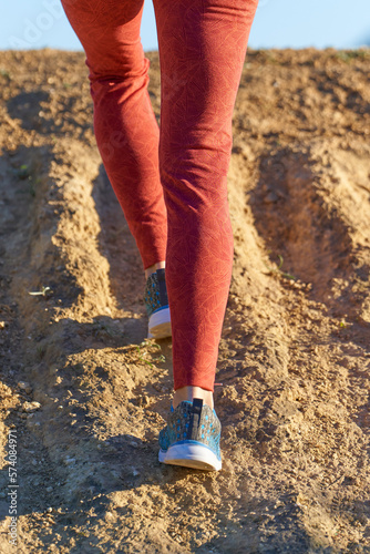 woman's legs wearing orange leggings close up walking trail