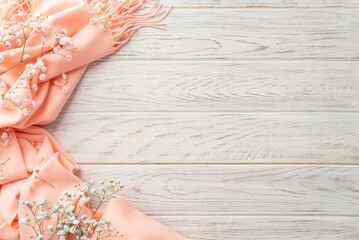 Hello spring concept. Top view photo of pink soft scarf and gypsophila flowers on grey wooden desk background with copyspace