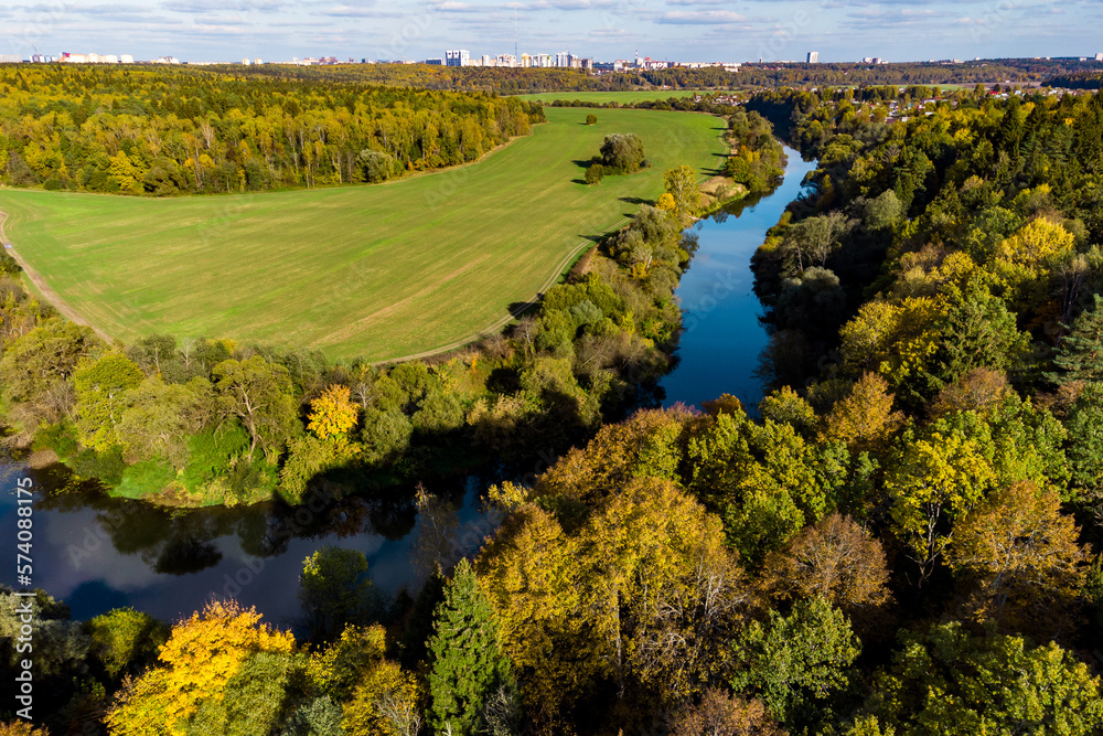 Trees height view of colorful landscape with river and fields in countryside, drone flight over autumn nature