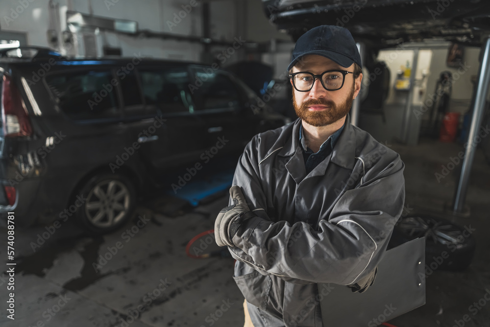 A mechanic crossing his arms and holding a writing pad in his hand. Dark background. High quality photo A mechanic crossing his arms and holding a writing pad in his hand. Dark background. High quality photo