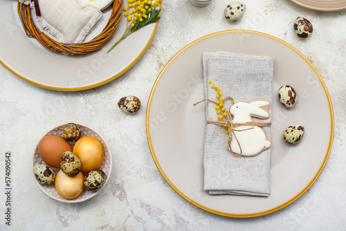 Table setting with Easter eggs and mimosa flowers on white grunge background