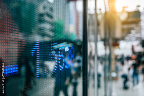 Financial stock exchange market display screen board on the street with and city light reflections, selective focus