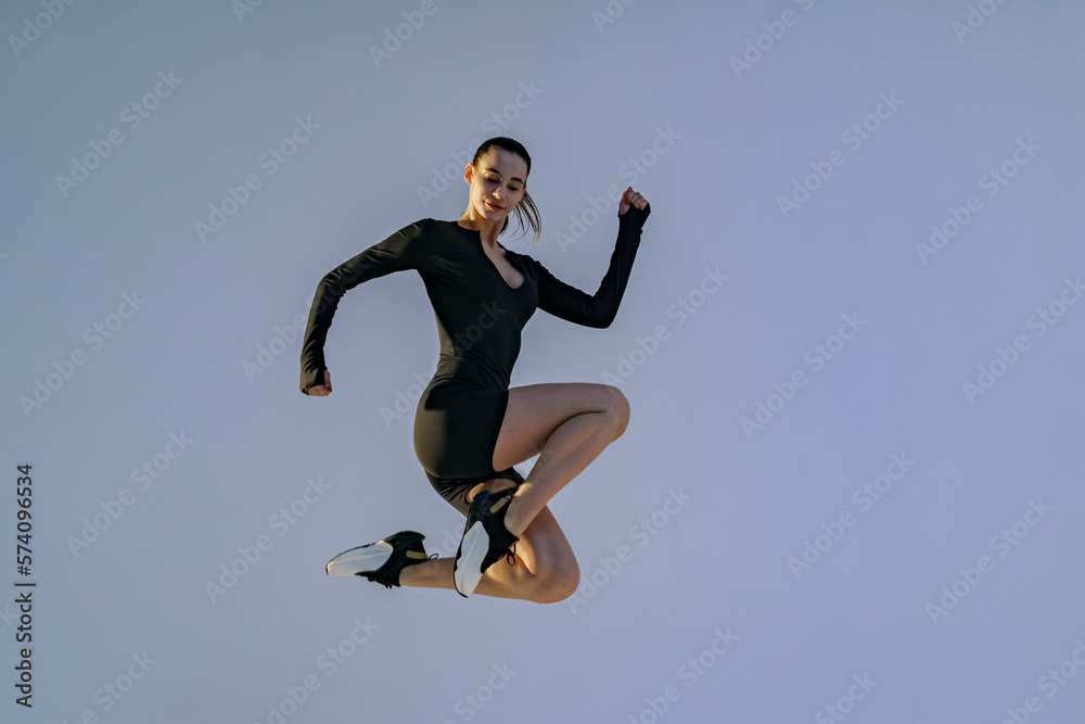 Athletic active woman jumping on studio background . Dynamic movement Athletic active woman jumping on studio background . Dynamic movement