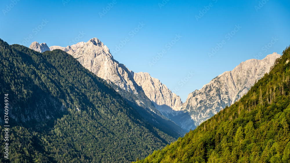 Triglav, the highest mountain in Slovenia. View from the Vrata Valley of the rocky summit and forested slopes of surrounding hills on a clear summer day