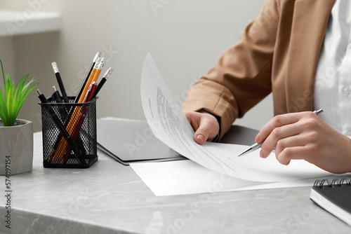 Billede på lærred Woman signing document at light grey marble table in office, closeup