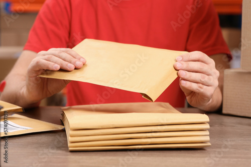 Post office worker with adhesive paper bags at counter indoors, closeup