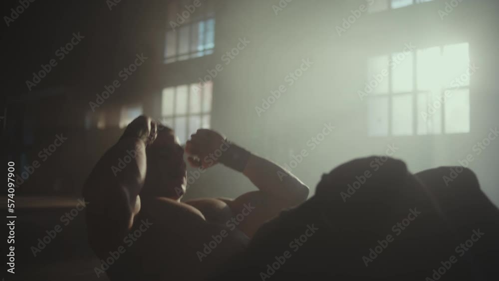 Shirtless muscular man doing sit-up exercise on the floor indoor in slow-motion Shirtless muscular man doing sit-up exercise on the floor indoor in slow-motion