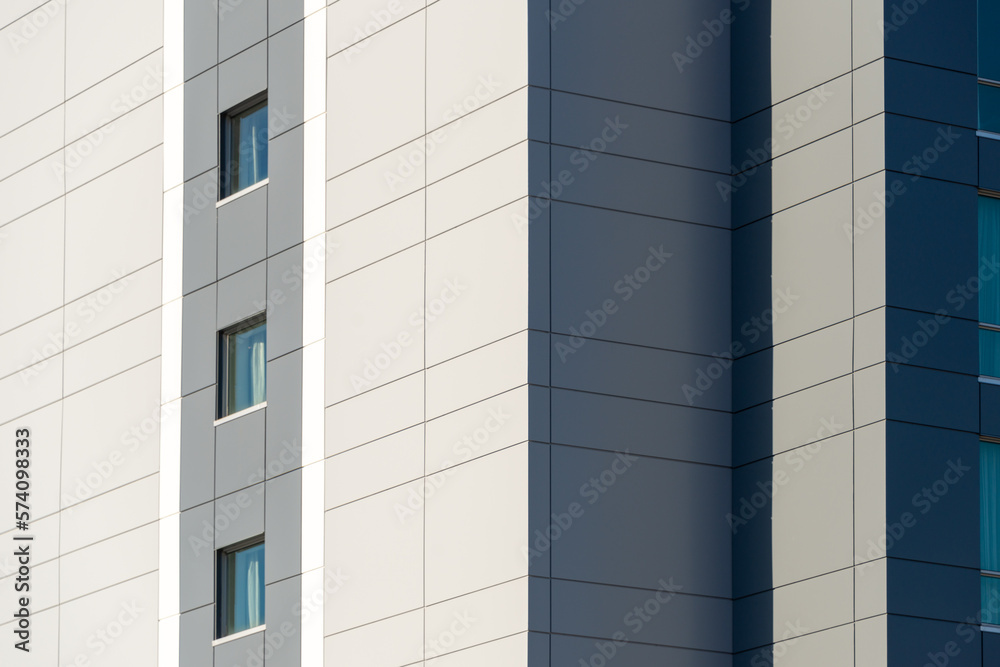 The exterior wall of a contemporary commercial style building with aluminum metal composite panels and glass windows. The futuristic building has engineered diagonal cladding steel frame panels. The exterior wall of a contemporary commercial style building with aluminum metal composite panels and glass windows. The futuristic building has engineered diagonal cladding steel frame panels.