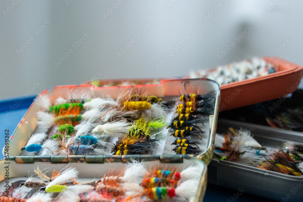 Multiple fly boxes of colorful salmon flies. The large selection is both dry and wet-style flies. The small single hooks have feathers, fur, and bright string surrounding the small fish hooks. Multiple fly boxes of colorful salmon flies. The large selection is both dry and wet-style flies. The small single hooks have feathers, fur, and bright string surrounding the small fish hooks.