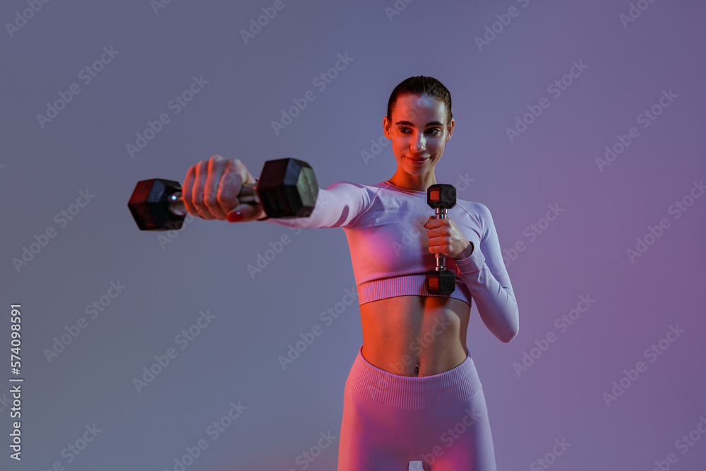 Woman doing exercises with dumbbells on studio background . Sport and healthy lifestyle