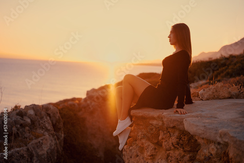 beautiful girl at dawn by the sea and rocks