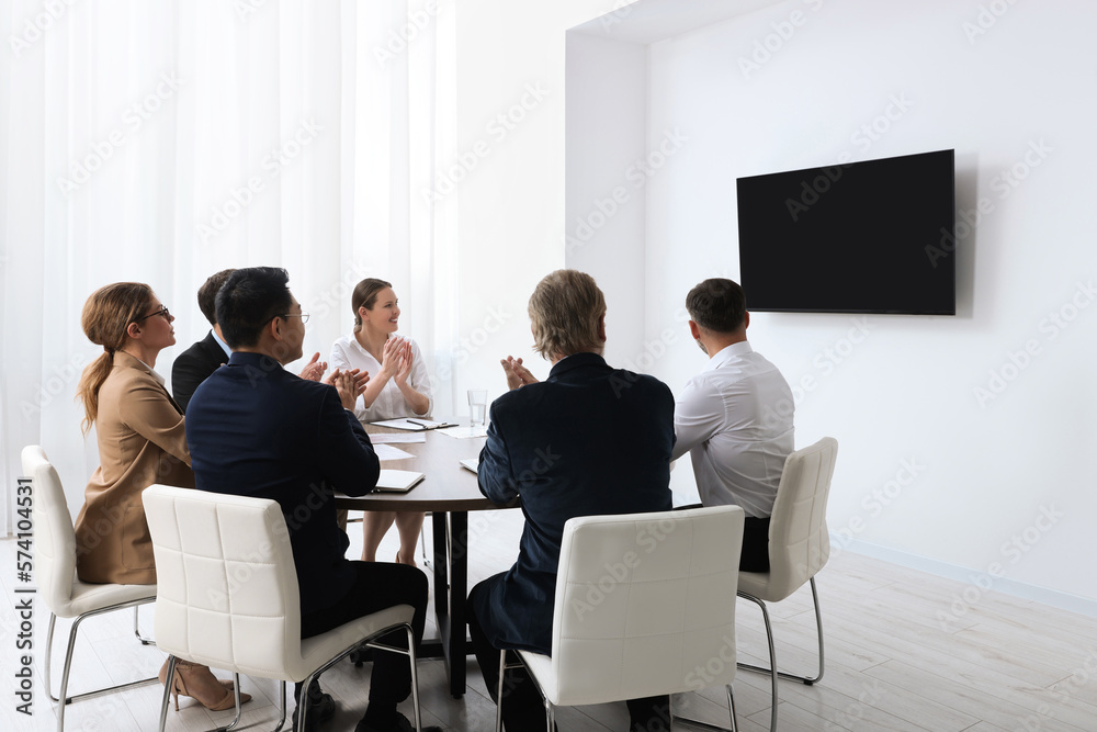 Business conference. Group of people watching presentation on tv screen in meeting room Business conference. Group of people watching presentation on tv screen in meeting room