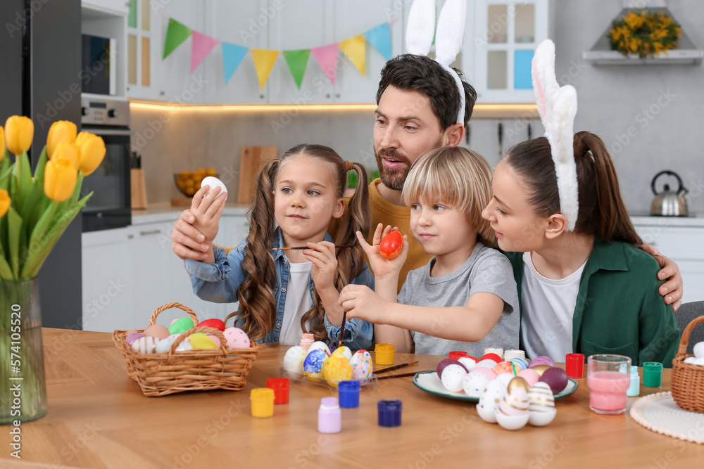 Happy family painting Easter eggs at table in kitchen Happy family painting Easter eggs at table in kitchen