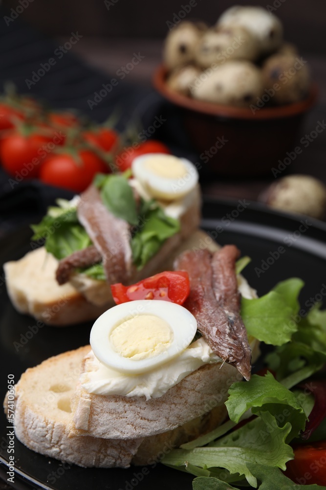 Delicious bruschettas with anchovies, cream cheese, arugula, eggs and tomatoes on table, closeup