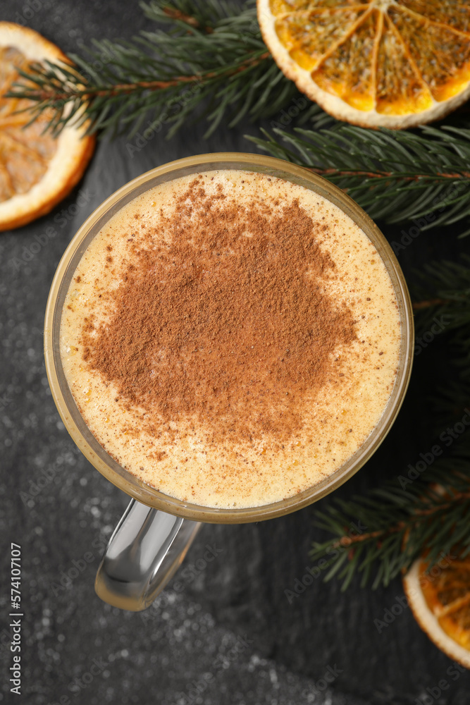Glass cup of delicious eggnog with cinnamon and dried orange slices on gray table, flat lay Glass cup of delicious eggnog with cinnamon and dried orange slices on gray table, flat lay