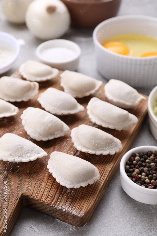 Raw dumplings (varenyky) and ingredients on grey table Raw dumplings (varenyky) and ingredients on grey table