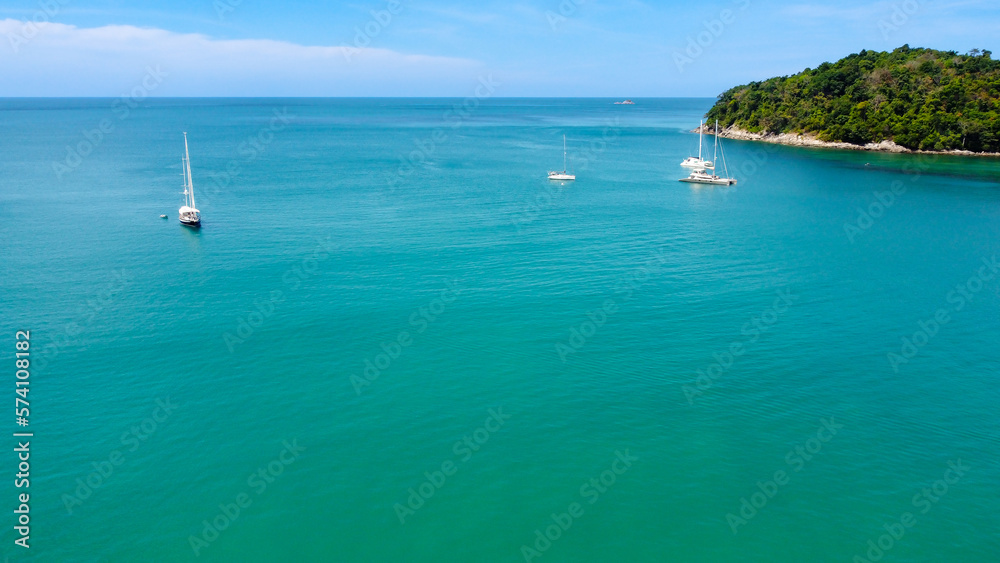Aerial view of luxury yacht in turquoise waters of Andaman Sea near Bang Tao beach, Phuket, Thailand. Beautiful view from above. 