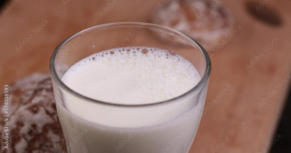 Bubbles of fresh milk in a clear glass glass, fresh milk in a glass and gingerbread on a dessert board Bubbles of fresh milk in a clear glass glass, fresh milk in a glass and gingerbread on a dessert board