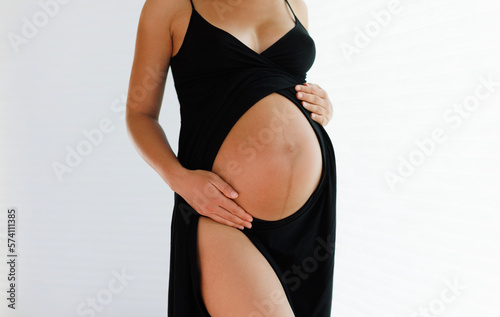 Pregnancy belly closeup. Pregnant woman elegant and beautiful wearing dress showing baby bump holding expecting tummy for skincare and health, lifestyle during pregnancy