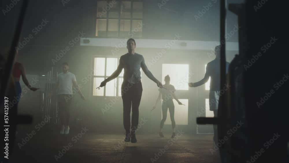 Athletes working out together in gym. Group of five people doing jumping rope exercise and two men cycling on exercise bike Athletes working out together in gym. Group of five people doing jumping rope exercise and two men cycling on exercise bike