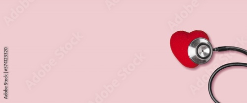 Red heart with medical stethoscope on desk