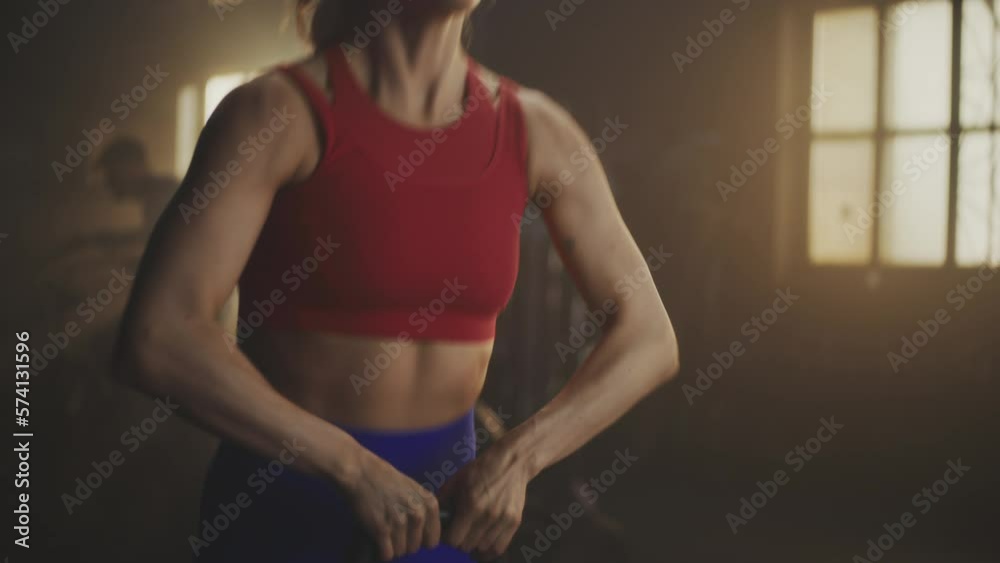 Tracking shot of fitness woman doing kettlebell exercise during crossfit workout at gym. People doing group exercise