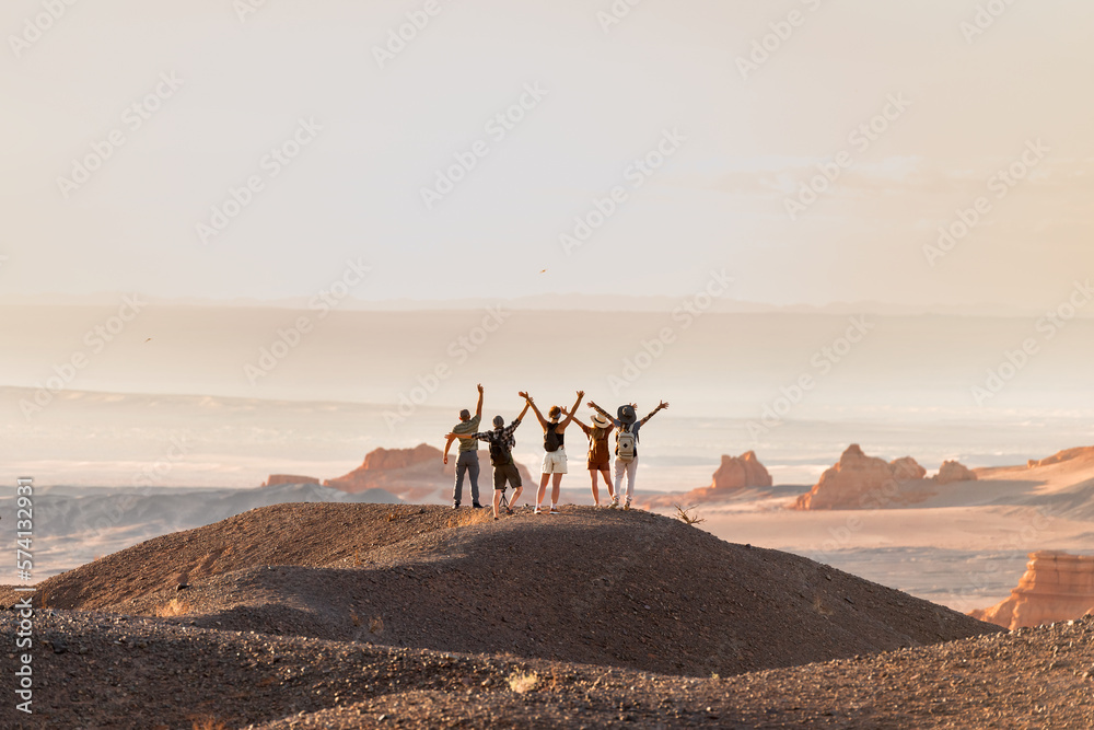 Group of happy tourists stands with open arms at desert view point - obrazy, fototapety, plakaty 