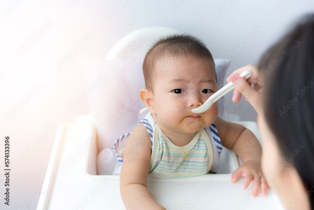 Asia baby boy child sitting eating food on chair at home Asia baby boy child sitting eating food on chair at home