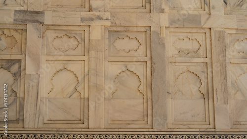 Details of the architecture of the ancient Taj Mahal. There are symmetrical decorative carvings and ornaments on the marble wall. India. Agra. Close-up