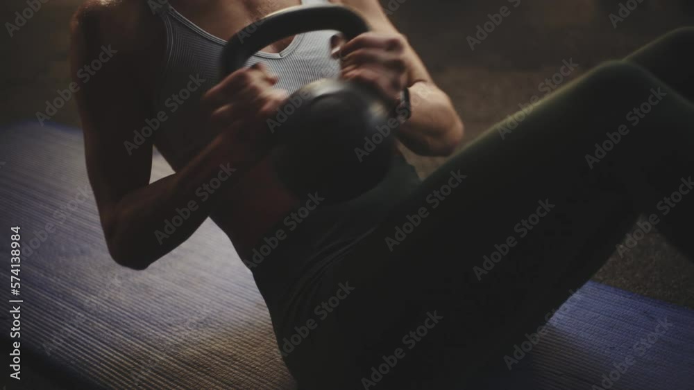 Woman exercising body weight with kettlebell twist and smiling at last while her friend doing cycling exercise in the background
