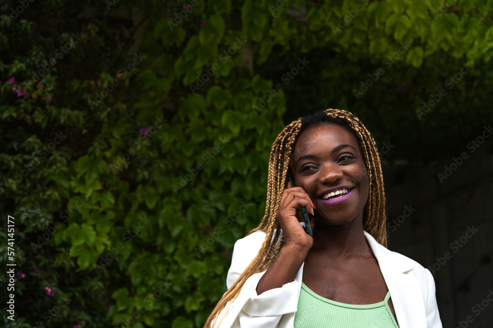 Fototapeta premium Happy Young Black woman talking on the phone outdoors. Copy space.