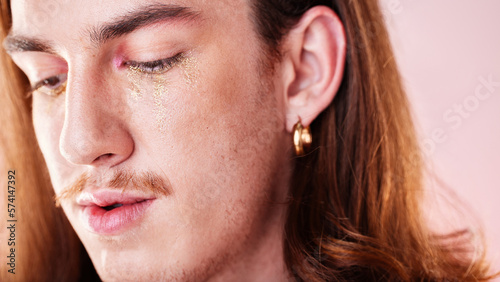 LGBTQ, makeup and gay man in a studio with a cyberpunk, androgynous and natural aesthetic. Creative, cosmetics and young queer male model with a cosmetic, glow and beauty face by a pink background.