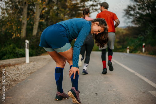 Obraz na plátně A woman standing and feeling the pain in her leg during jogging