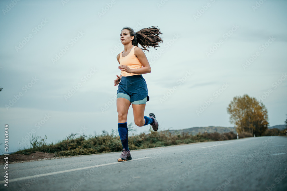 Female athlete with long hair running outdoors early in the morning during her cardio routine. Copy space Female athlete with long hair running outdoors early in the morning during her cardio routine. Copy space