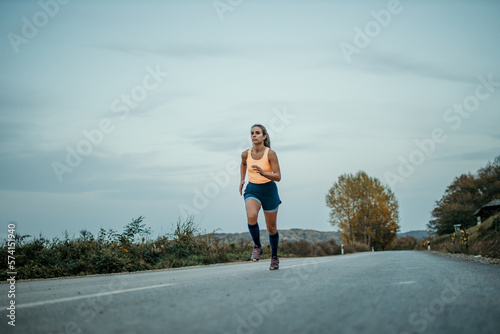 Female athlete with long hair running at full speed outdoors early in the morning during her cardio routine. 