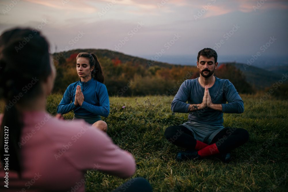 Three people meditating outdoors. Two people followed a guided meditation from a female yoga tutor.