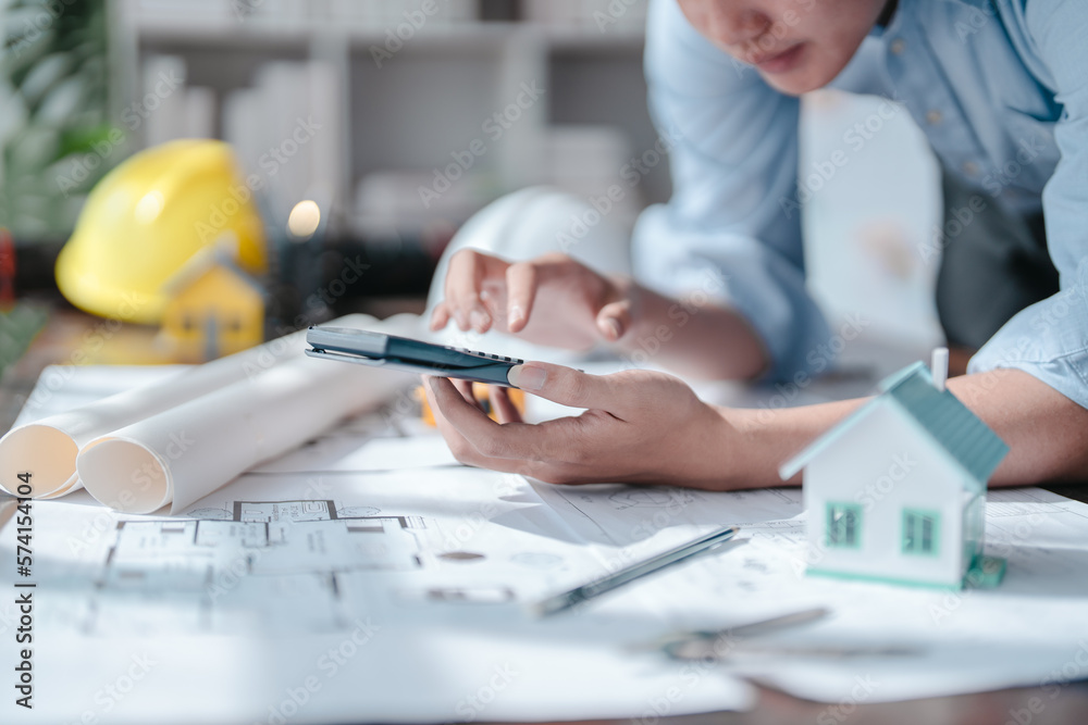 Fototapeta premium Drawing construction plan remodel and renovate and old house at meeting team engineer desk in office building. Using calculator