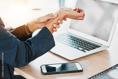 Business, closeup and woman with wrist pain, burnout and laptop in office, stress and deadline. Zoom, female employee and professional with smartphone, injury and muscle strain in workplace and hand
