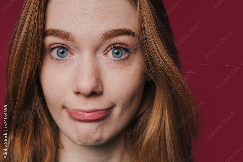 Naklejka premium Picture of young woman with red hair looking at camera with thoughtful and sly expression. Modern style. Fashion style. People lifestyle portrait. Beautiful