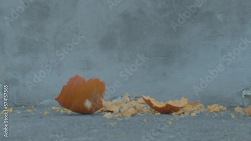 Halloween pumpkin is smashed into pieces in slow motion after being dropped onto ground. photo