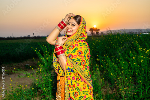 Portrait of beautiful young indian punjabi woman model wearing colorful traditional standing posing at agriculture field outdoor. photo