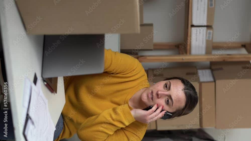 Female online seller or web store owner confirming orders from customer on the phone. SME or freelance business online and delivery concept. Female online seller or web store owner confirming orders from customer on the phone. SME or freelance business online and delivery concept.
